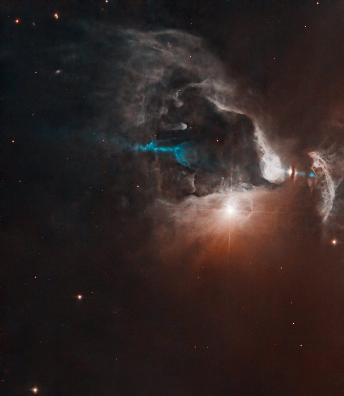 FS Tau B A bright point of light shines near center-right with diffraction spikes, surrounded by glowing clouds against black space. A blue jet of material extends roughly throughout the center of the image, partially obscured by the clouds.