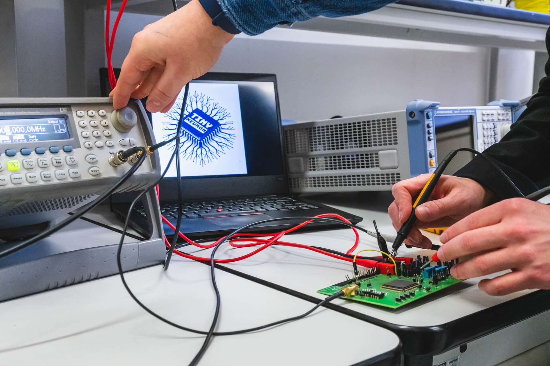 La strumentazione utilizzata dai progettisti di “TinyNeuron - Silicon Neuron for AI” e, sullo schermo del computer, il logo del progetto