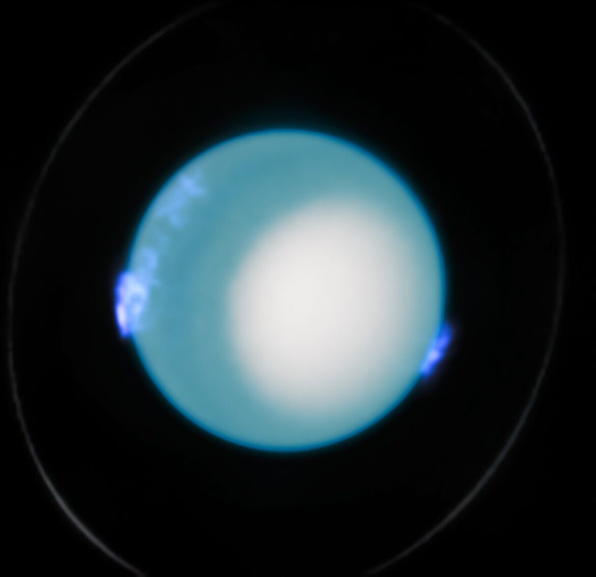 This Hubble image shows Uranus and dynamic aurora activity on 10 October 2022. The centered planet is dominated by a blue hue and a large white region in the lower left. A faint ring is also visible around the planet. Fuzzy blue/purple regions hovering over the planet on the left and ride indicate the presence of aurorae.
