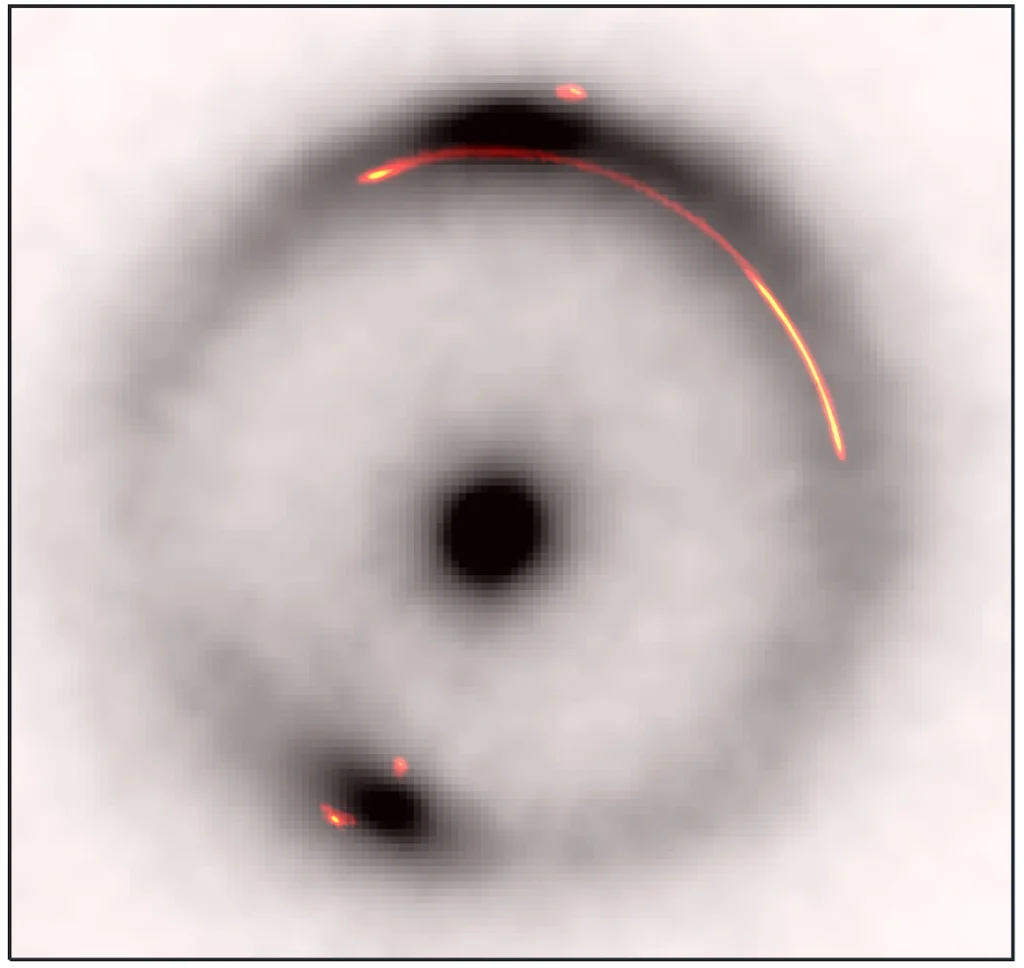 Sovrapposizione dell'emissione infrarossa (in bianco e nero) con l'emissione radio (a colori) dell’arco gravitazionale del sistema JVAS B1938+666. L'oggetto oscuro e di piccola massa si trova nel vuoto nella parte luminosa dell'arco sul lato destro. Crediti: Keck/EVN/GBT/VLBA/John McKean